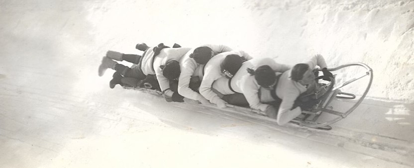 black and white photo of five people on a bobsled