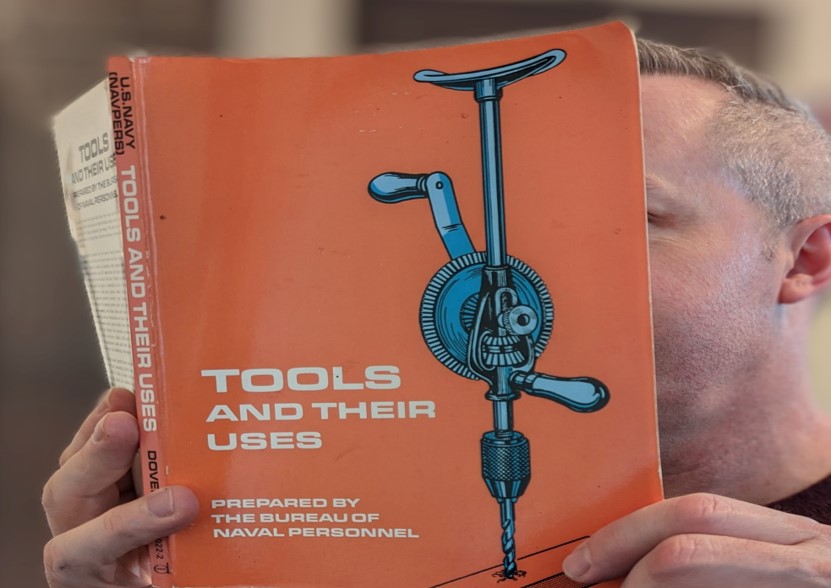 an orange book titled tools and their uses, featuring a blue diagram of a manual drill